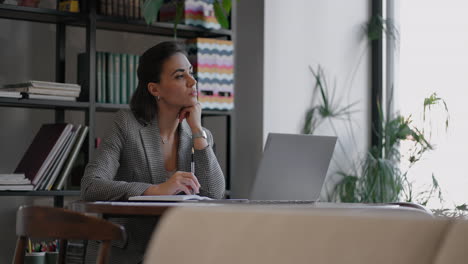 Arabian-Hispanic-woman-working-financial-paperwork-seated-at-workplace-using-laptop-looks-concentrated-while-makes-task-prepare-check-report-having-fruitful-workday.-Student-learning-process-concept